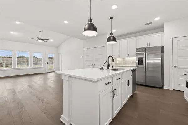a kitchen with stainless steel appliances granite countertop a sink a stove a refrigerator and a dining table with wooden floor