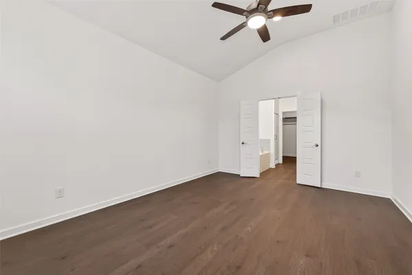 an empty room with wooden floor and ceiling fan