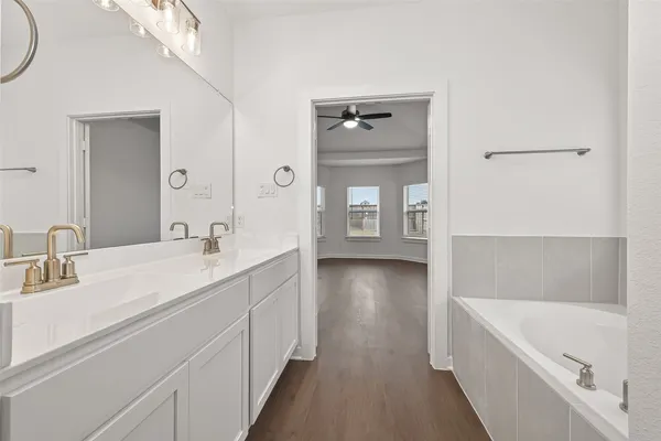 a en suite bathroom with a double vanity sink a mirror and a bathtub
