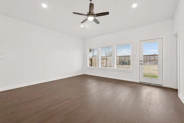 a view of an empty room with wooden floor and a window