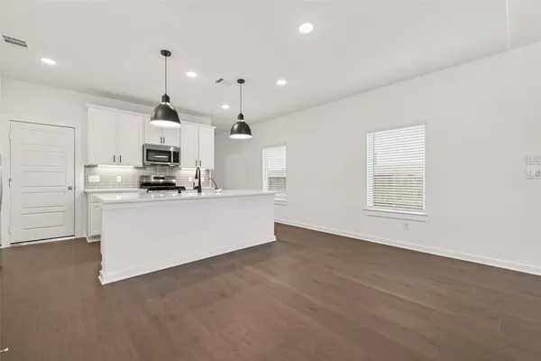 a view of kitchen with kitchen island stainless steel appliances a sink a stove a microwave and cabinets