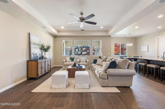 a living room with furniture a large window and wooden floor