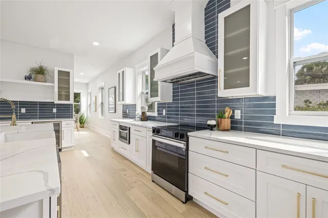 a kitchen with stainless steel appliances kitchen island granite countertop a stove a sink and white cabinets
