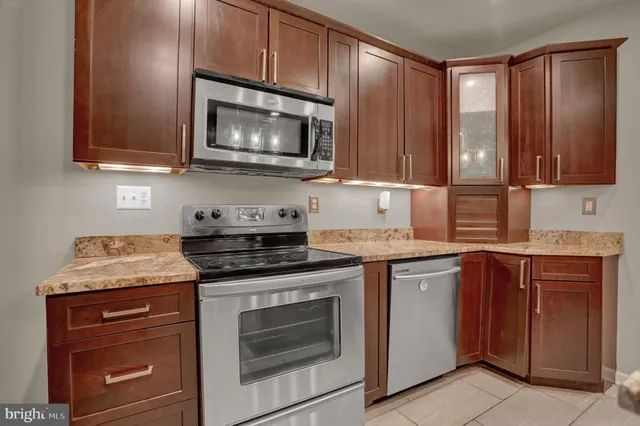 a kitchen with granite countertop wooden cabinets and a stove top oven
