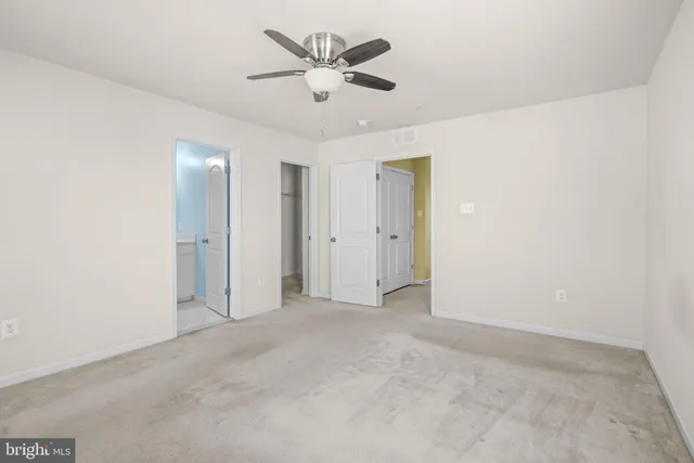 an empty room with ceiling fan and window