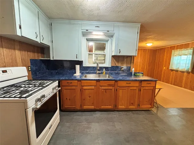 a kitchen with granite countertop a sink a stove and cabinets