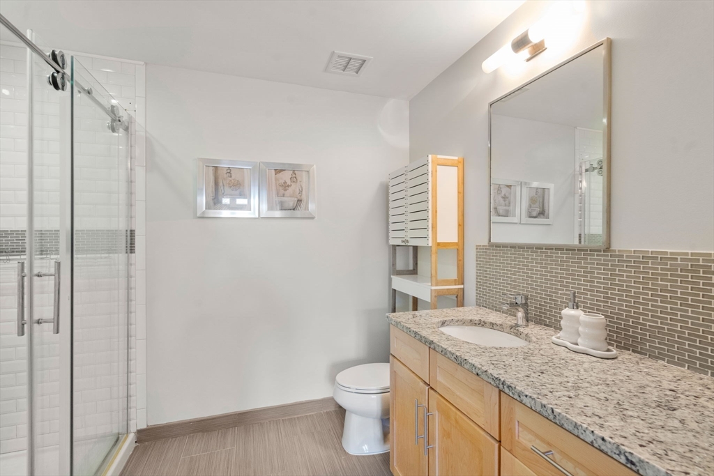 1501 Commonwealth Avenue, Unit 409 Boston, MA 02135 - Photo 11 of 17 a bathroom with a granite countertop sink toilet and shower