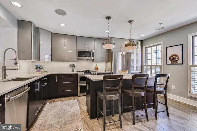 a kitchen with stainless steel appliances granite countertop a sink a stove and a wooden floors
