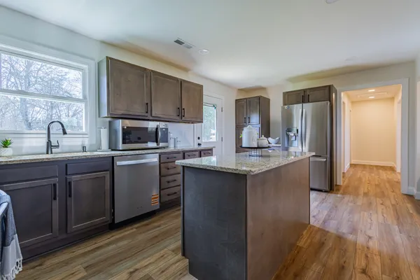 a kitchen with kitchen island granite countertop wooden floors and stainless steel appliances