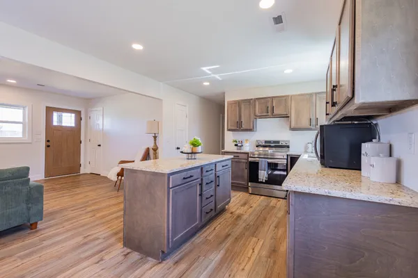 a kitchen with stainless steel appliances granite countertop wooden cabinets a sink a stove a refrigerator and a center island