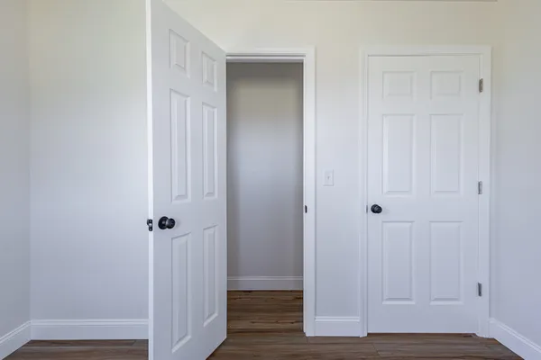 an empty room with wooden floor chandelier fan and windows