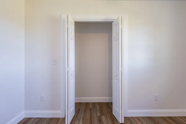 an empty room with wooden floor chandelier fan and windows