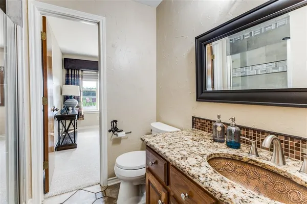 a bathroom with a granite countertop toilet sink and mirror