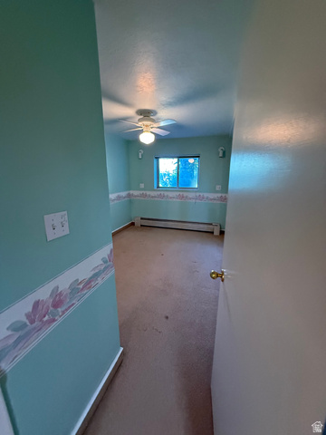 328 Heather Ridge Circle Sandy, UT 84070 - Photo 27 of 32 Interior room featuring a ceiling fan with integrated lighting, a window, baseboard heating, and wall-mounted sconces
