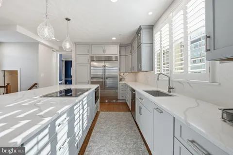 a large kitchen with kitchen island a large window a sink and stainless steel appliances