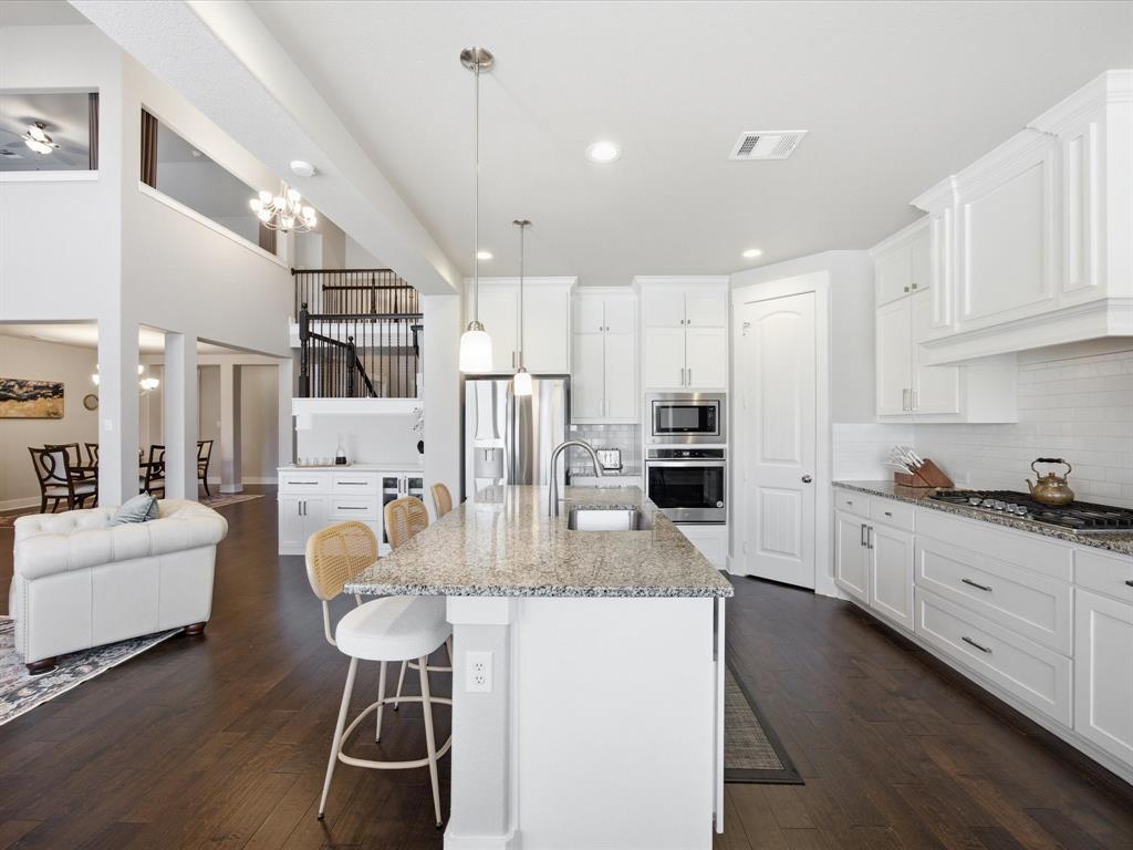 146 Old Bridge Road Waxahachie, TX 75165 - Photo 18 of 40 a kitchen with stainless steel appliances kitchen island granite countertop a stove a refrigerator a oven and white cabinets with wooden floors