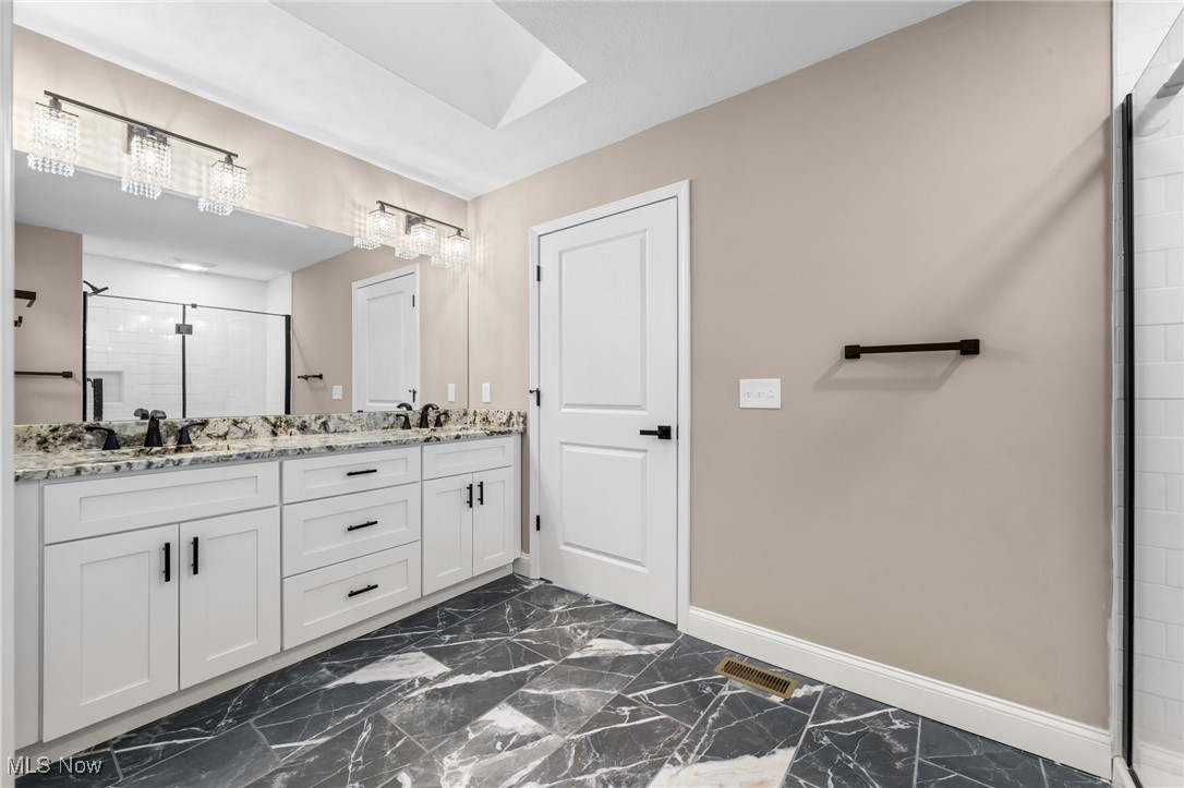 39600 Aurora Road Solon, OH 44139 - Photo 29 of 49 Bathroom with a stall shower, double vanity, a skylight, and dark marble finish flooring