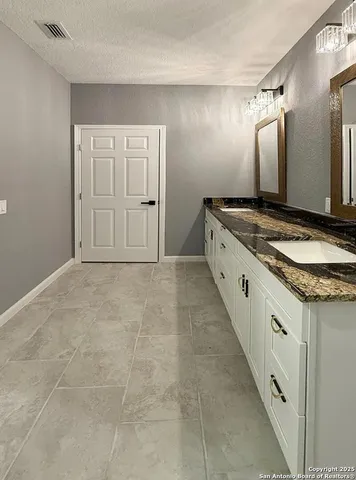 a bathroom with a granite countertop double vanity sink and a mirror