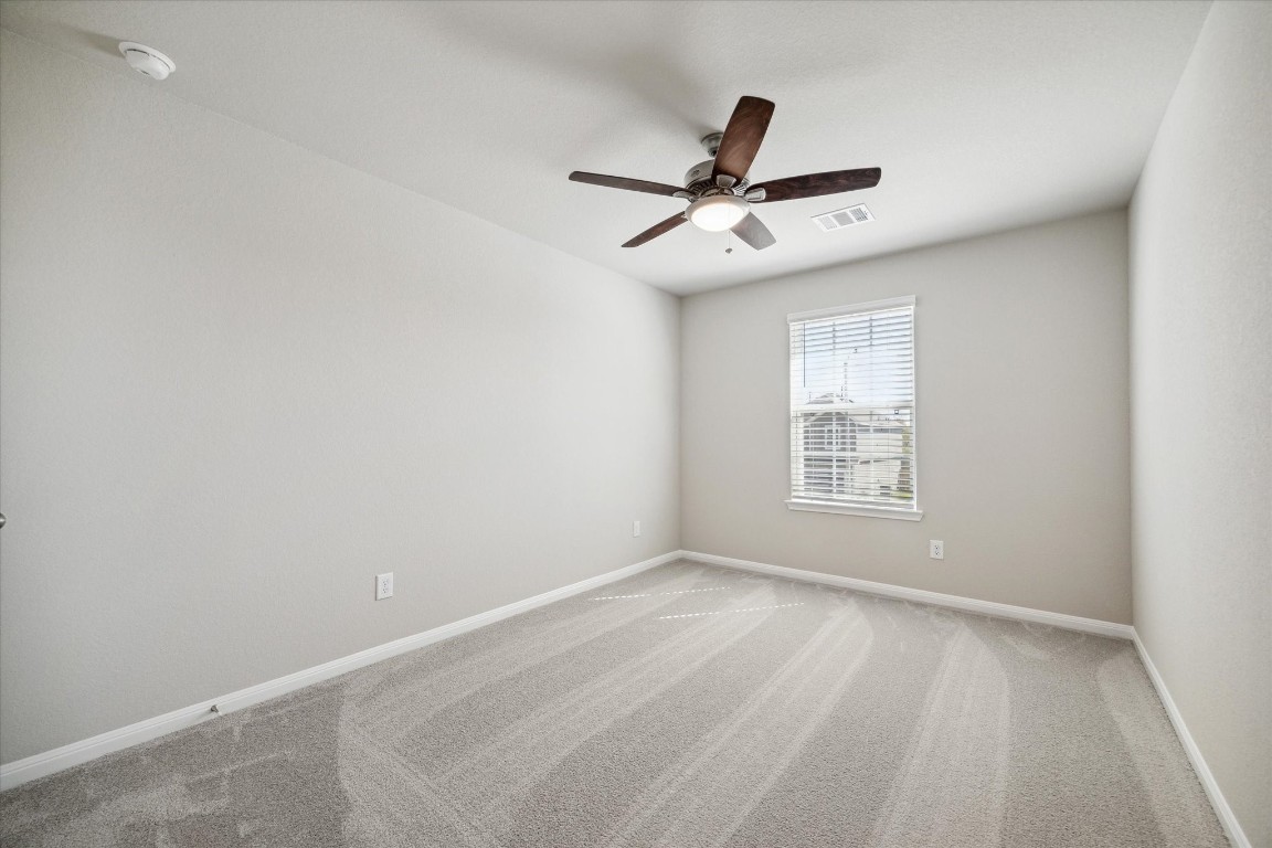 715 Gavin Walker Drive Rosharon, TX 77583 - Photo 11 of 15 This photo showcases a bright, unfurnished bedroom with neutral walls and carpet. It features a ceiling fan and a window with blinds, providing natural light and airflow.