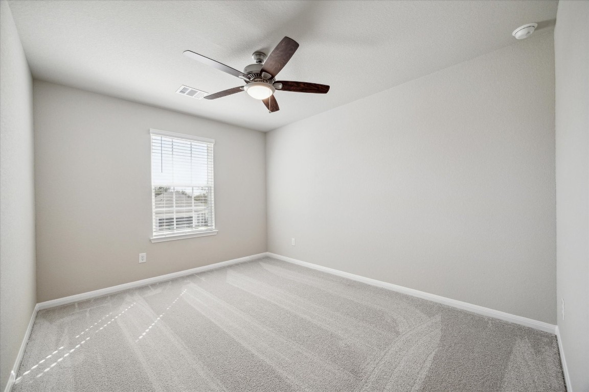 715 Gavin Walker Drive Rosharon, TX 77583 - Photo 12 of 15 This photo shows a bright, empty room with light gray walls and carpet, featuring a ceiling fan and a window with blinds. Ideal for a bedroom or office space.