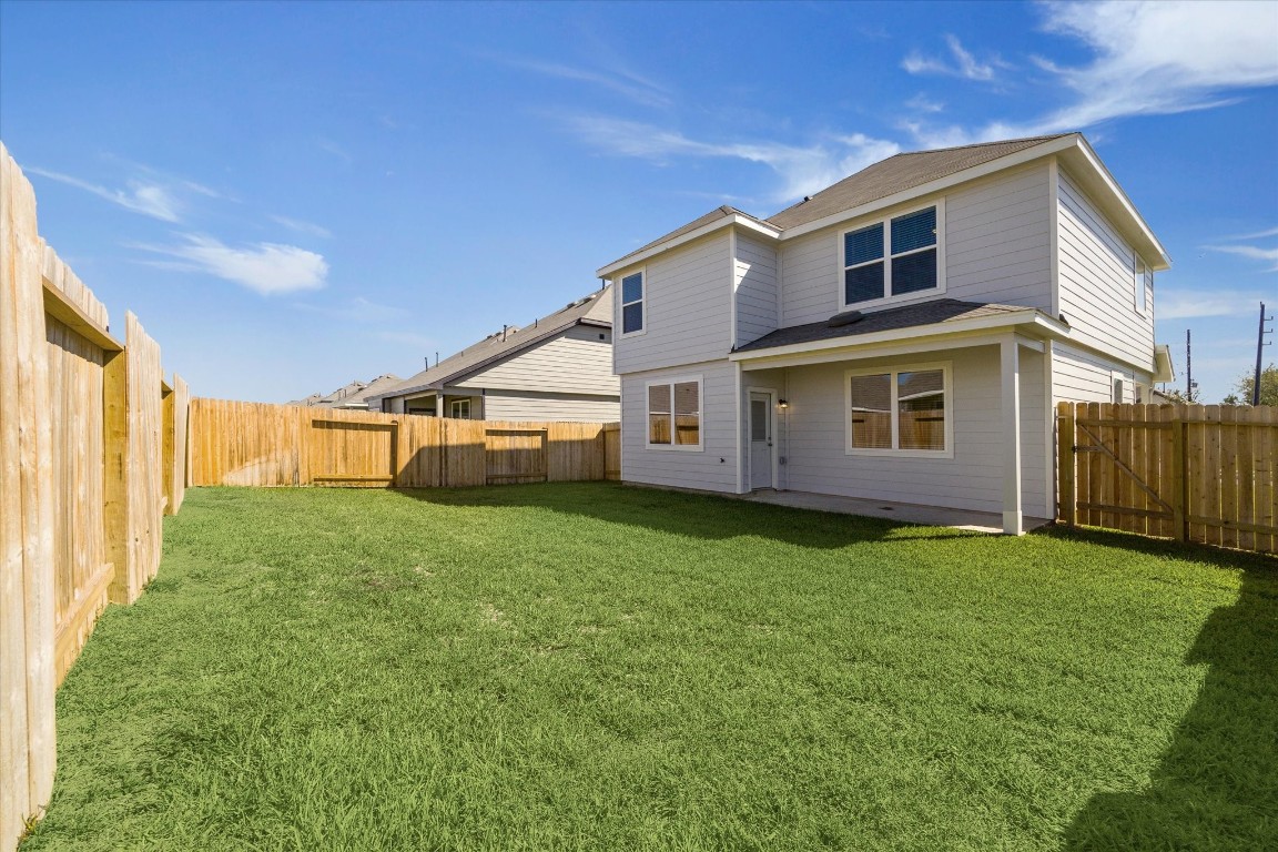 715 Gavin Walker Drive Rosharon, TX 77583 - Photo 2 of 15 This photo shows a spacious two-story home with a large, fenced backyard featuring lush green grass. The exterior is modern with multiple windows for natural light, set against a clear blue sky. Perfect for outdoor activities and privacy.