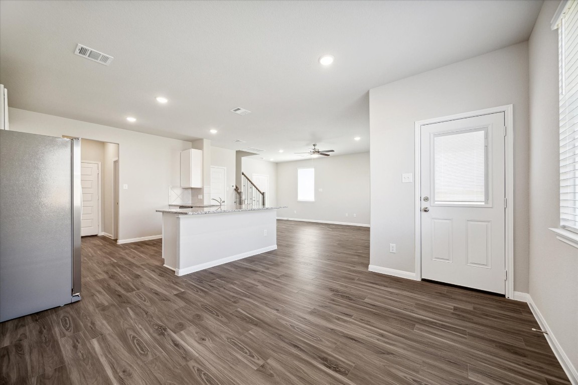 715 Gavin Walker Drive Rosharon, TX 77583 - Photo 5 of 15 This photo showcases a spacious open-concept living area with modern wood flooring and recessed lighting. The kitchen features a large island with granite countertops and stainless steel appliances. The neutral color palette and ample natural light create a bright, inviting atmosphere.
