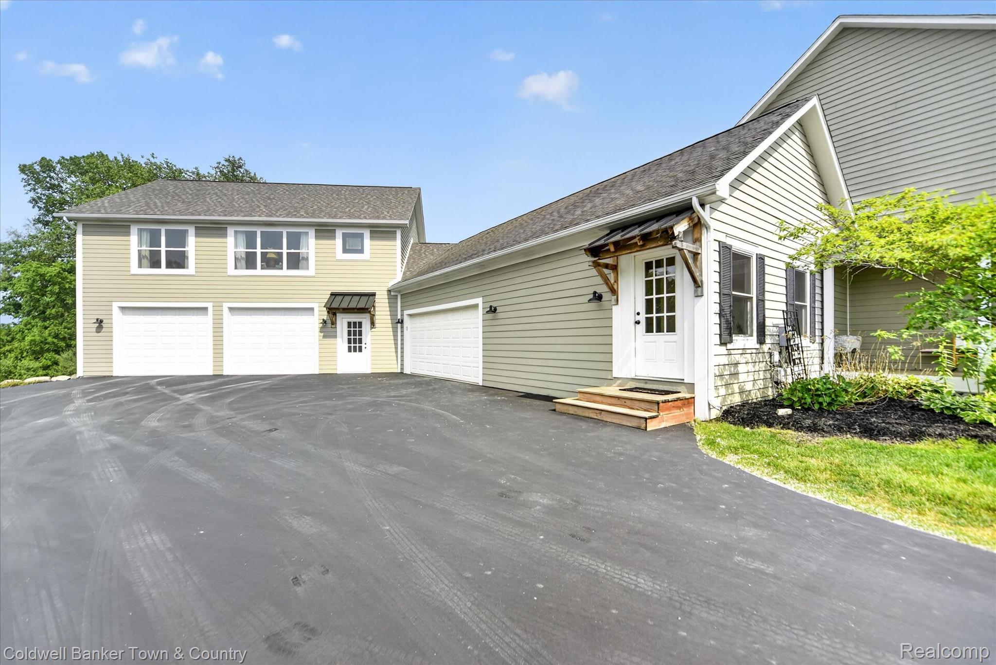 918 Gray Fox Court Howell, MI 48843 - Photo 5 of 84 Multi-level property exterior featuring light green siding, a spacious asphalt driveway, and three garage doors