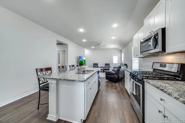 a kitchen with stainless steel appliances kitchen island granite countertop a stove a sink and a microwave