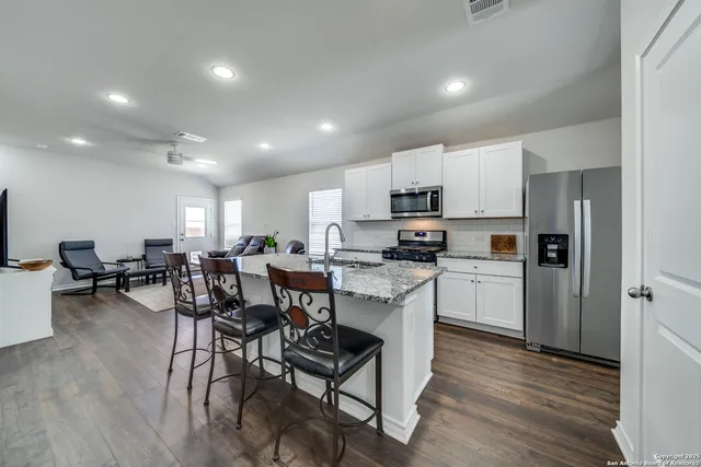 a open dining room with stainless steel appliances a dining table chairs refrigerator and cabinets