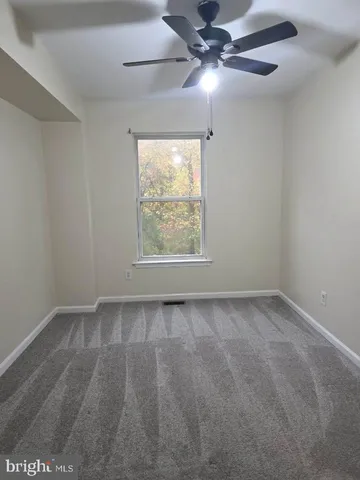 an empty room with a window and a fan