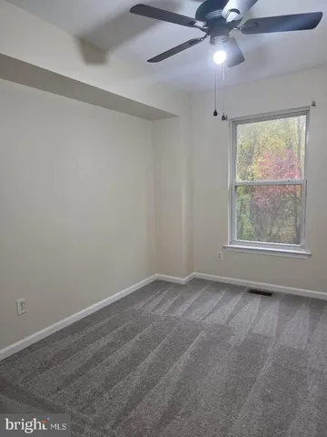 an empty room with a window and a fan