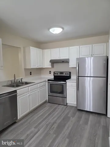 a kitchen with granite countertop white cabinets and stainless steel appliances