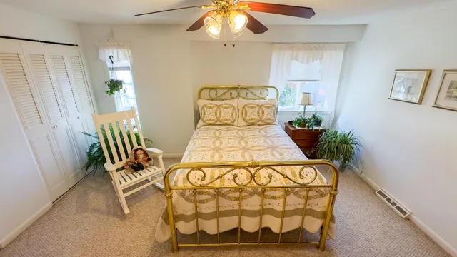 a bed sitting in a bedroom next to a window and a chandelier