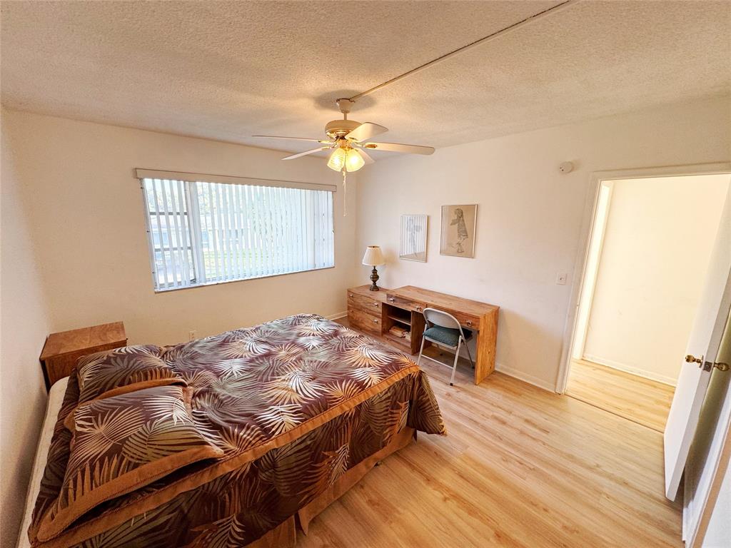 310 South Cypress Road, Unit 729 Pompano Beach, FL 33060 - Photo 22 of 30 a bedroom with a bed and wooden floor