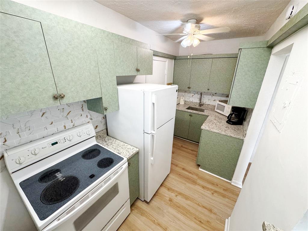 310 South Cypress Road, Unit 729 Pompano Beach, FL 33060 - Photo 7 of 30 a kitchen with a stove cabinets and wooden floor