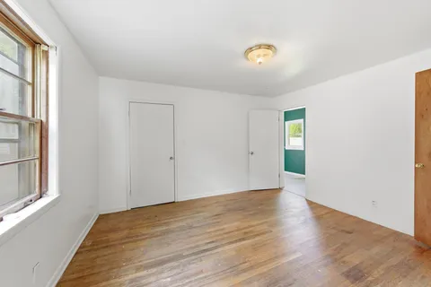 a view of an empty room with wooden floor and windows