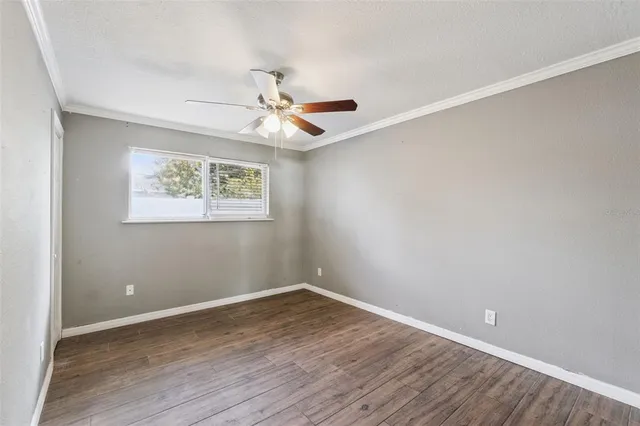 an empty room with wooden floor ceiling fan and windows