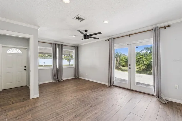 a view of an empty room with a window and wooden floor