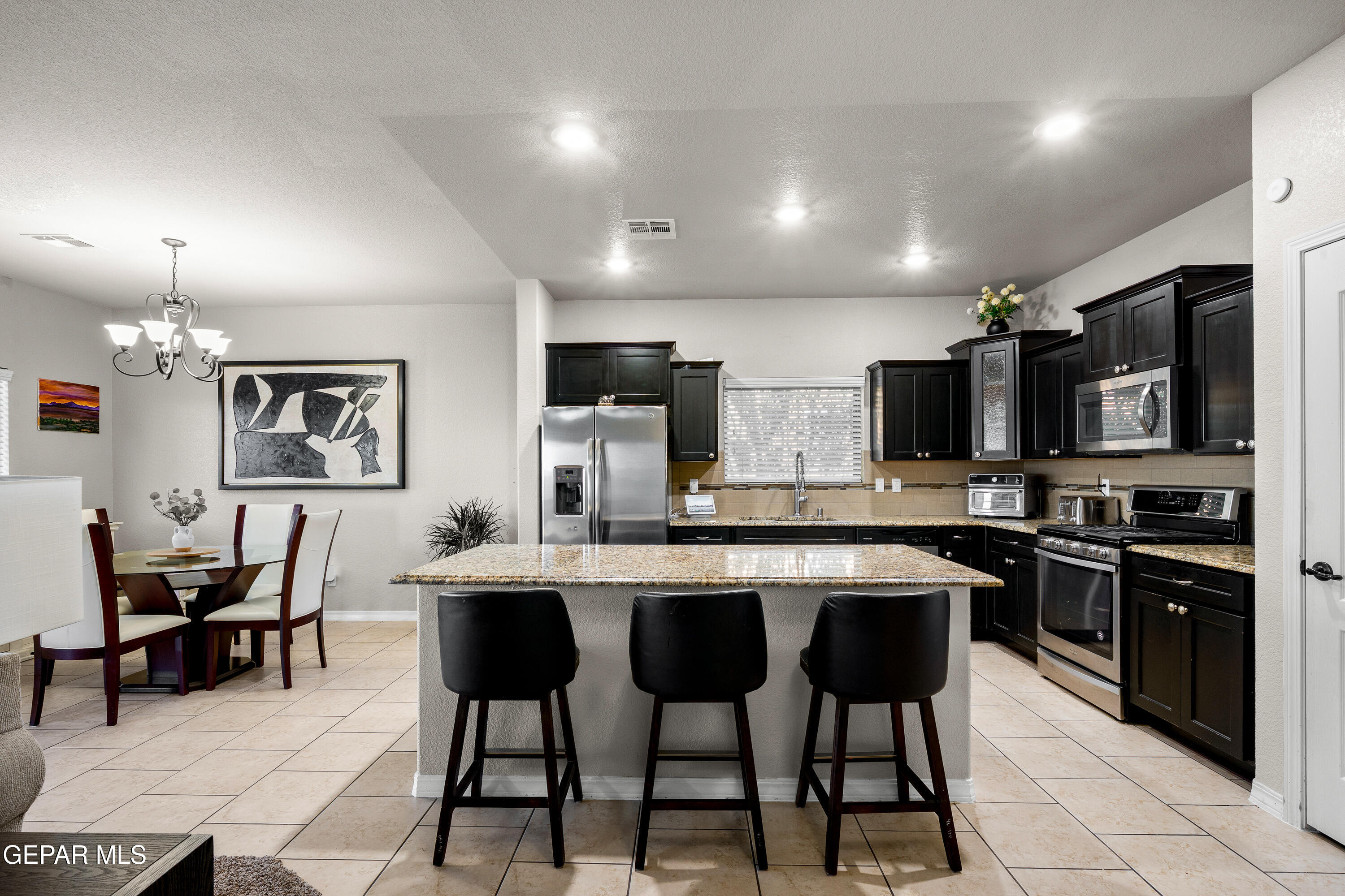 7755 Enchanted Path Drive El Paso, TX 79911 - Photo 7 of 34 a kitchen with stainless steel appliances a dining table and chairs