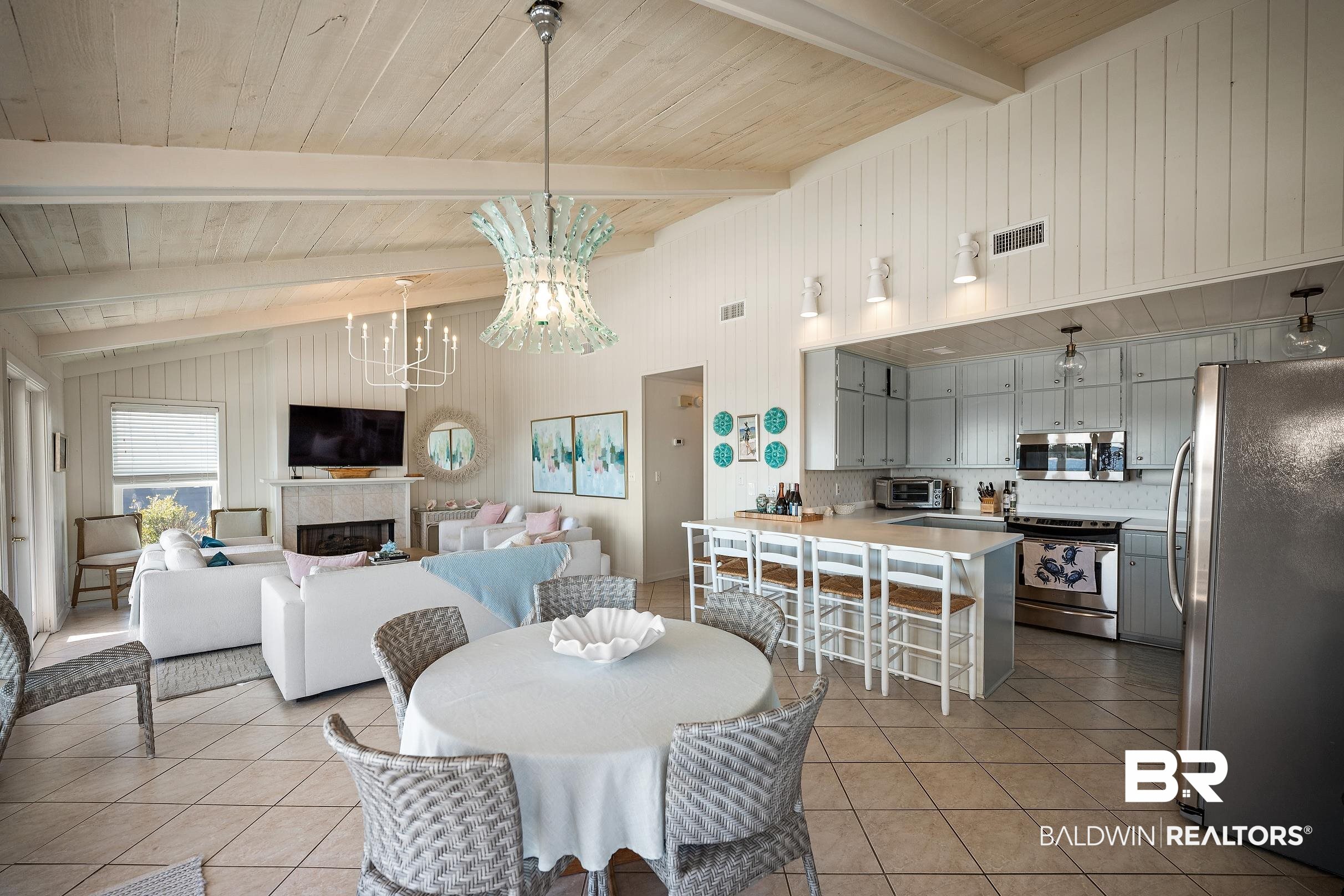 32620 River Road Orange Beach, AL 36561 - Photo 14 of 60 Dining area with hanging lights, a fireplace, wood walls, light tile patterned flooring, and a high wooden beamed ceiling