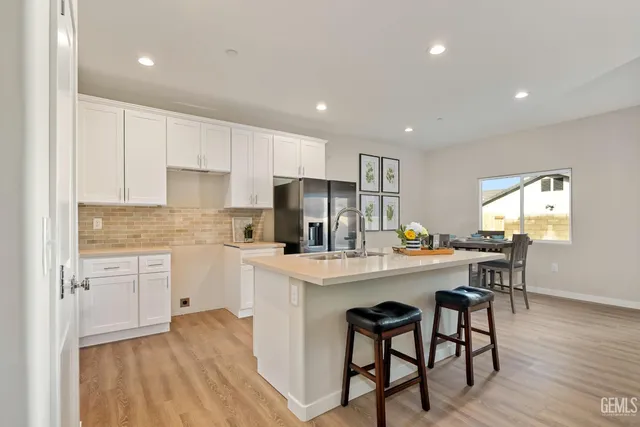 a kitchen with stainless steel appliances granite countertop a refrigerator a sink a stove a dining table and chairs