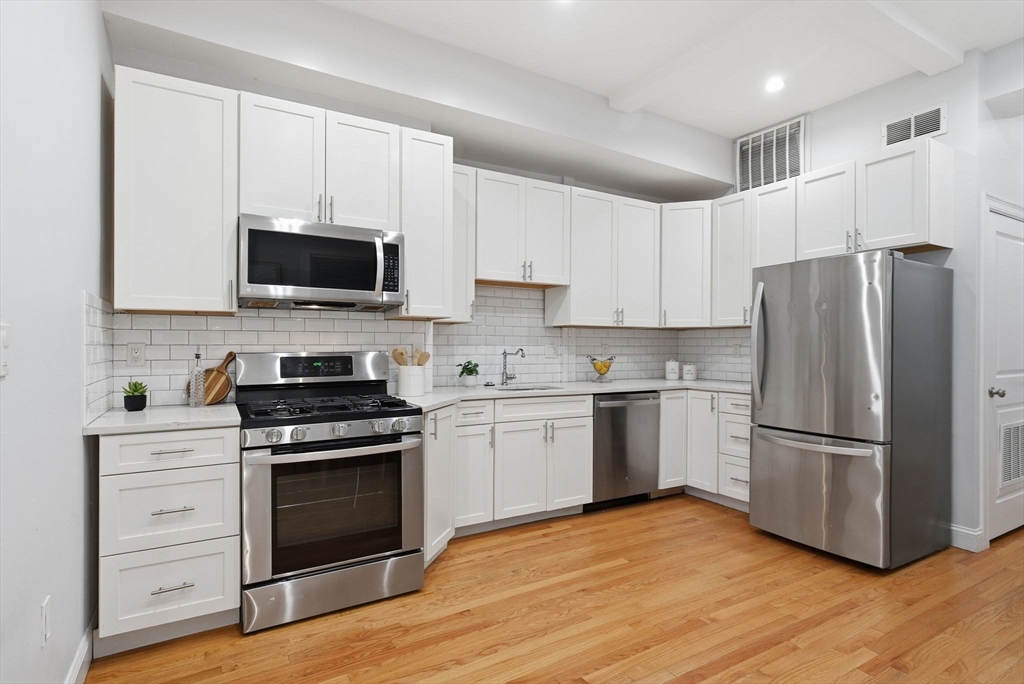 80 Marion Street, Unit 2 Boston, MA 02128 - Photo 3 of 33 a kitchen with cabinets stainless steel appliances and wooden floor