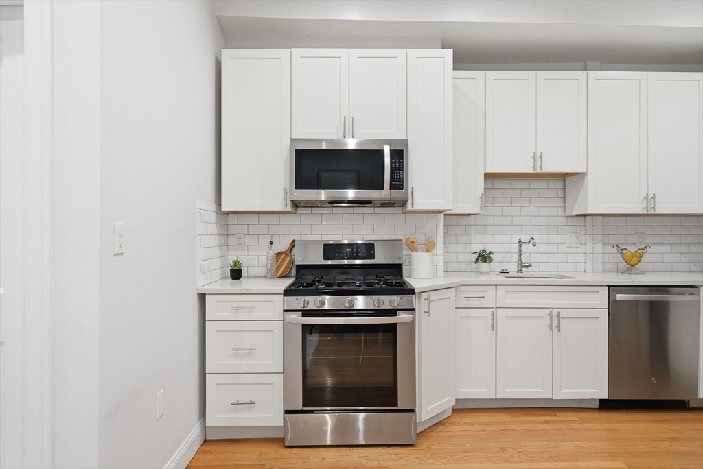 80 Marion Street, Unit 2 Boston, MA 02128 - Photo 3 of 33 a kitchen with white cabinets and stainless steel appliances
