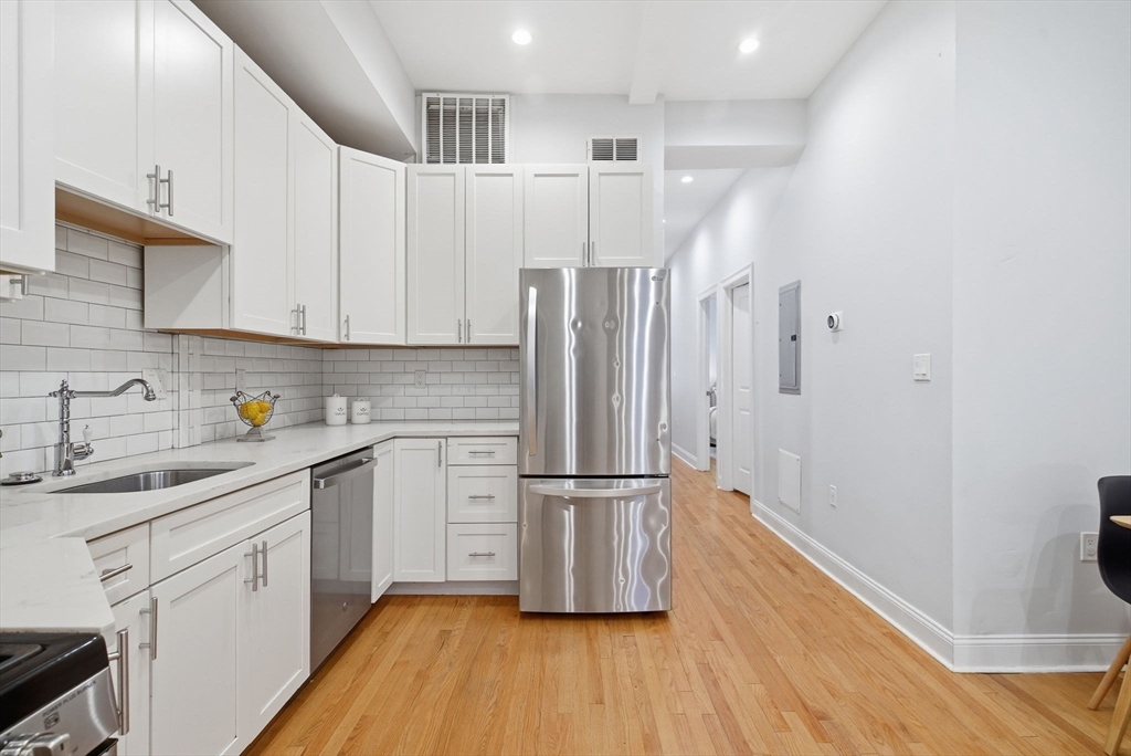 80 Marion Street, Unit 2 Boston, MA 02128 - Photo 5 of 33 a kitchen with a refrigerator wooden floor and white cabinets