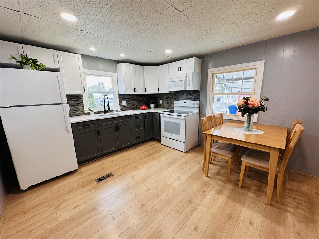 70 Shumway Street, Unit A3 Springfield, MA 01119 - Photo 3 of 28 a kitchen with a refrigerator a stove a dining table and chairs with wooden floor