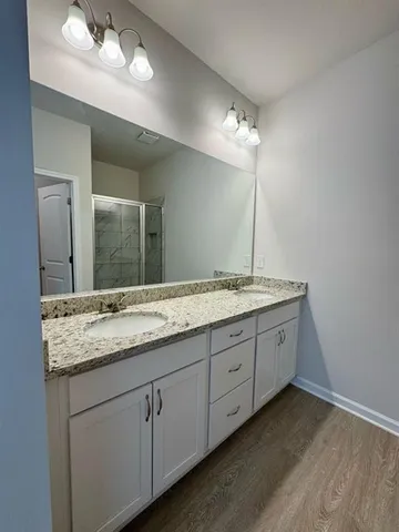 a bathroom with double vanity sink a vanity and a large mirror