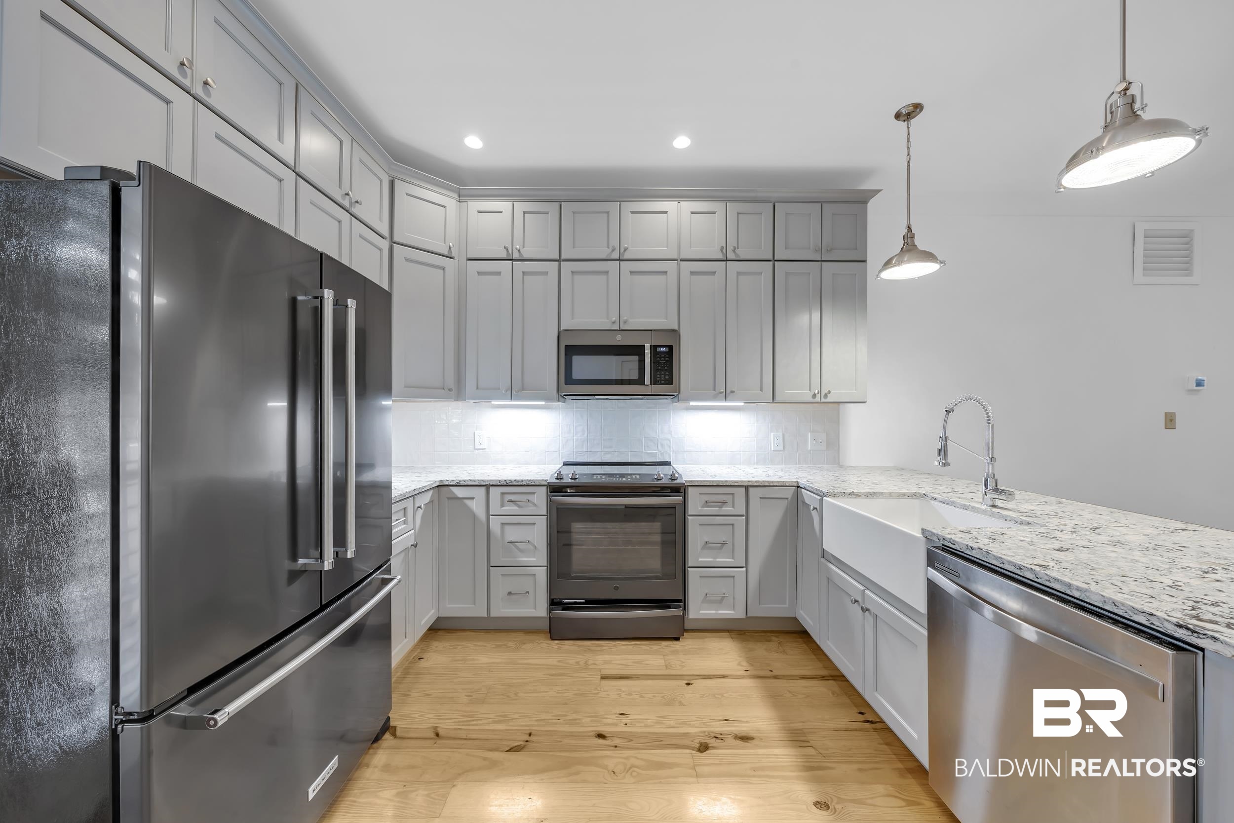 25773 Canal Road, Unit 32 Orange Beach, AL 36561 - Photo 5 of 35 Kitchen featuring stainless steel appliances, light stone counters, hanging light fixtures, light wood-type flooring, and gray cabinets