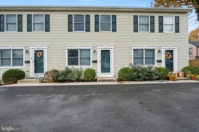 a view of a house with a yard and potted plants