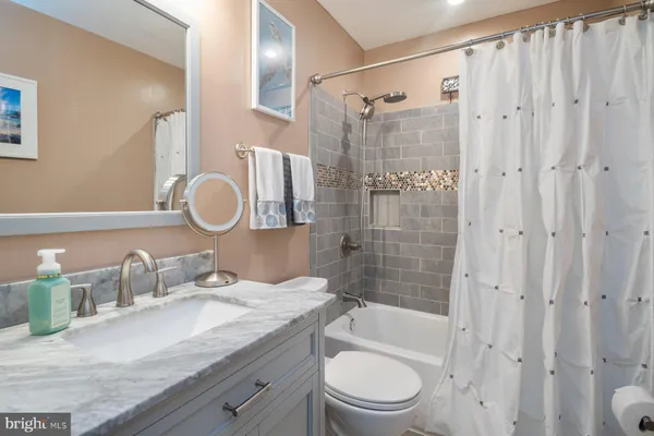 a bathroom with a granite countertop sink a toilet and shower