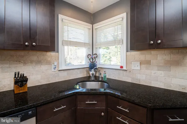 a kitchen with granite countertop wooden cabinets a sink and a window